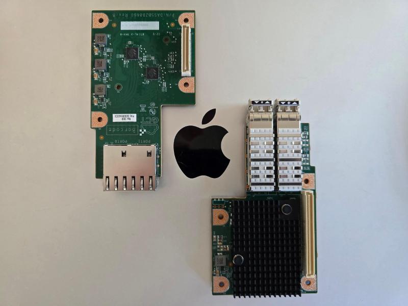 Two OCP NICs placed on a MacBook lid on either side of the Apple logo, showing the difference between the original 1GbE NIC and the new 25GbE NIC